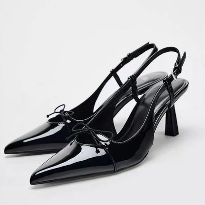 Black patent leather bow with pointed tip thin heel and a shallow strap for women's sandals